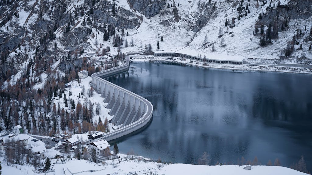 Snow-covered Fedaia Dam and lake in Trentino, Italy, during winter.