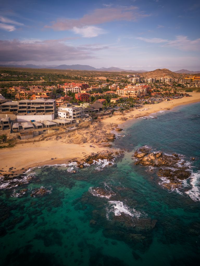 Scenic aerial view of Cabo San Lucas beach and coastline, showcasing stunning rocky shores under a summer sky.