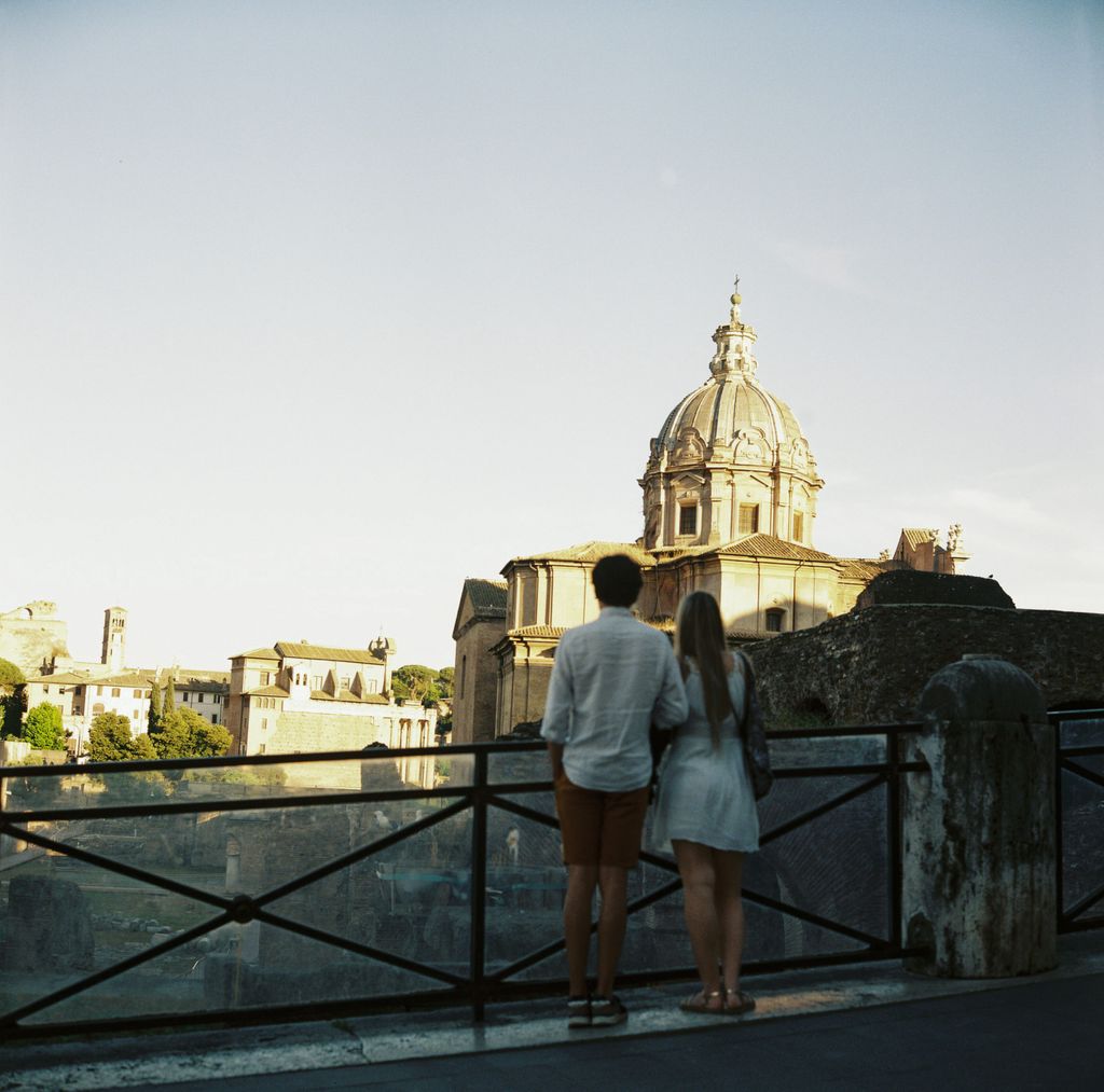 A couple enjoys a sunset view of classic Roman architecture in Rome, Italy.