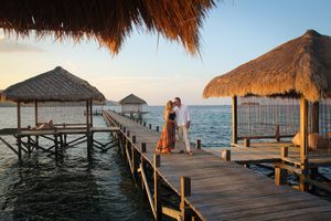 A couple shares a romantic moment on a wooden pier under thatched roofs in East Nusa Tenggara, Indonesia.